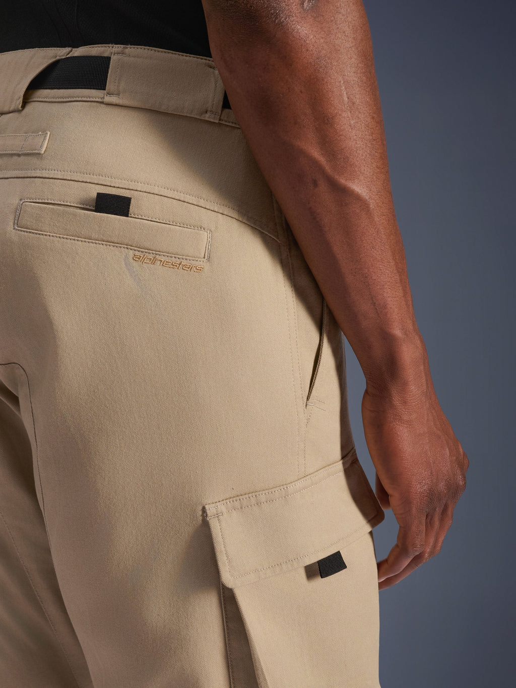 Alpinestars Flex-AST Cargo Pants - Short, beige chiaro, vista laterale ravvicinata che mostra la tasca cargo con linguetta nera e logo ricamato sulla tasca posteriore, materiale tessile resistente, abbigliamento da moto urbano