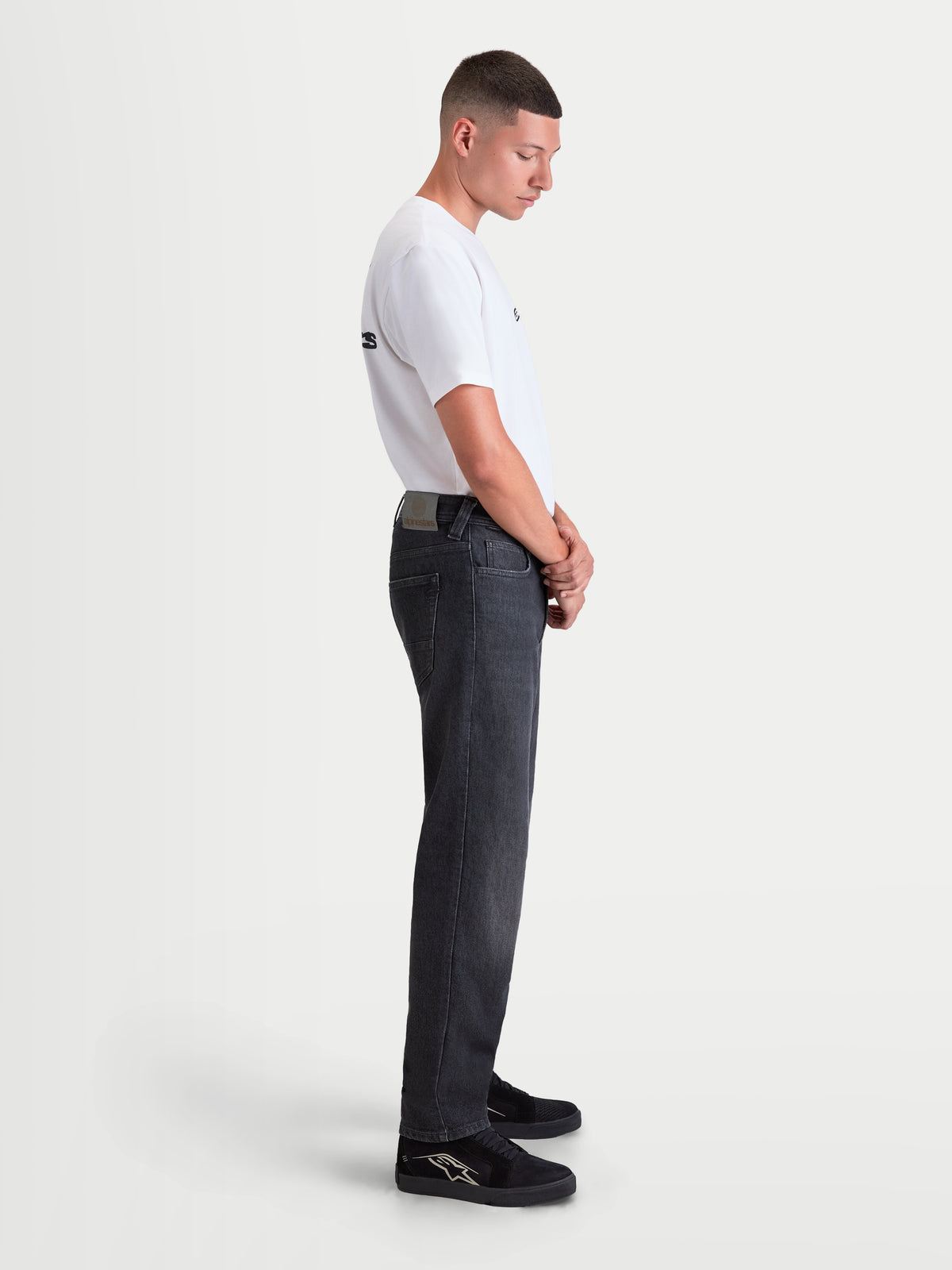 Alpinestars Flex Ast 8 Denim Pantaloni, pantaloni da moto urban contemporary da uomo in colore nero slavato, vista laterale su un modello che indossa una t-shirt bianca e scarpe da moto casual, denim monostrato protettivo con certificazione AA