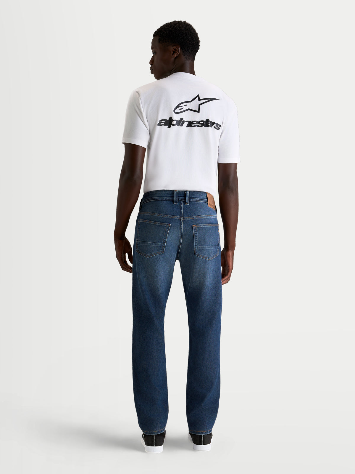 Alpinestars Flex-AST 8 Denim Pantaloni, jeans da moto urbani da uomo in blu medio, vista posteriore con struttura in denim tecnico monostrato e classico stile a cinque tasche indossati da un modello