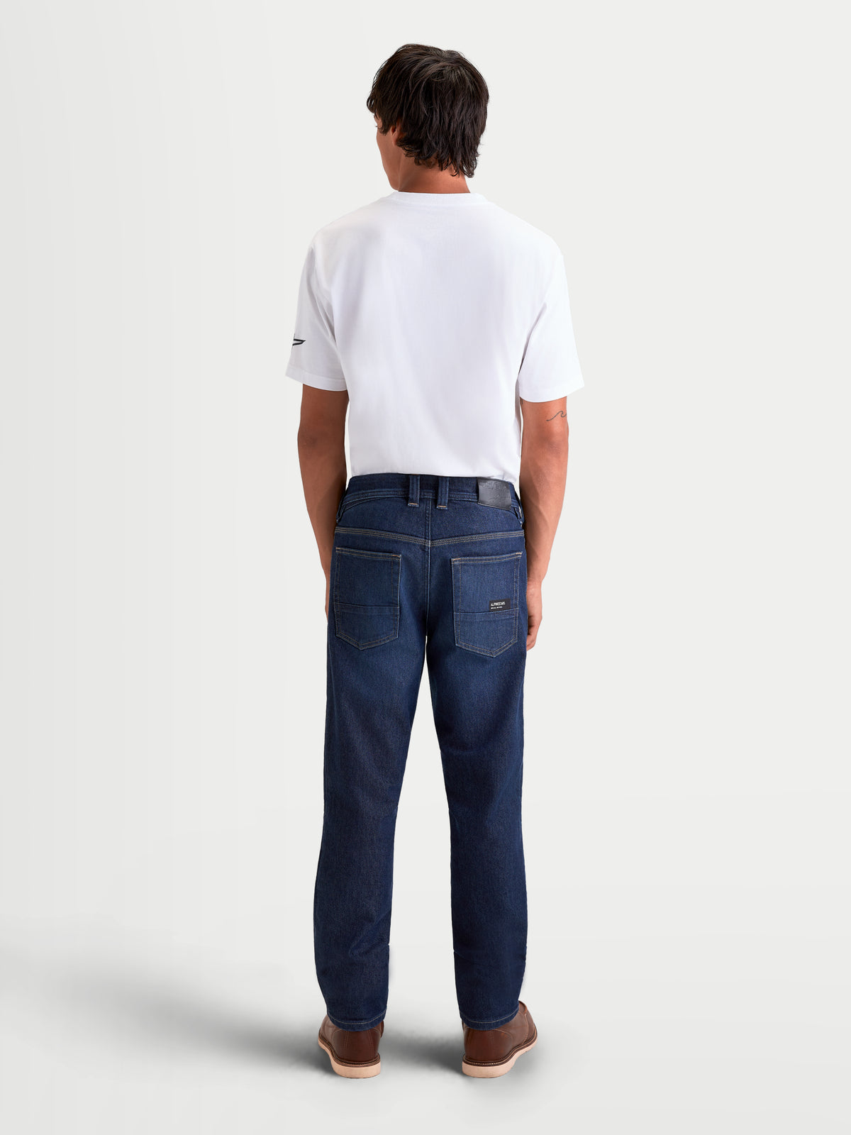 Alpinestars Flex Ast 7 Denim Pantaloni, pantaloni da moto urban da uomo in blu scuro, vista posteriore con costruzione in denim tecnico a strato singolo, toppa in pelle sul retro e dettaglio ricamato Astar sulla tasca indossati da un modello