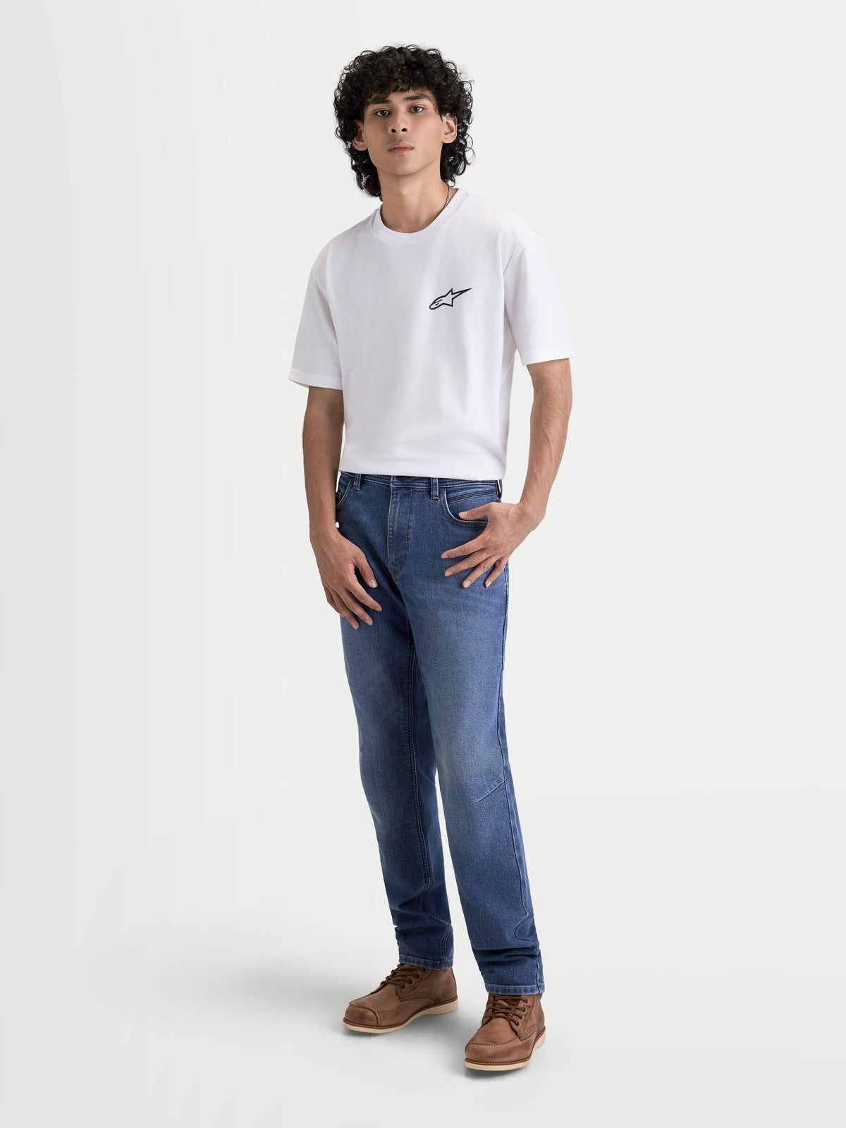 Alpinestars Flex Ast 7 Denim Pantaloni, jeans da moto urbani contemporanei da uomo in colore azzurro, vista frontale completa su un modello che indossa una maglietta bianca e stivali marroni, denim protettivo monostrato omologato AA con comfort COOLMAX