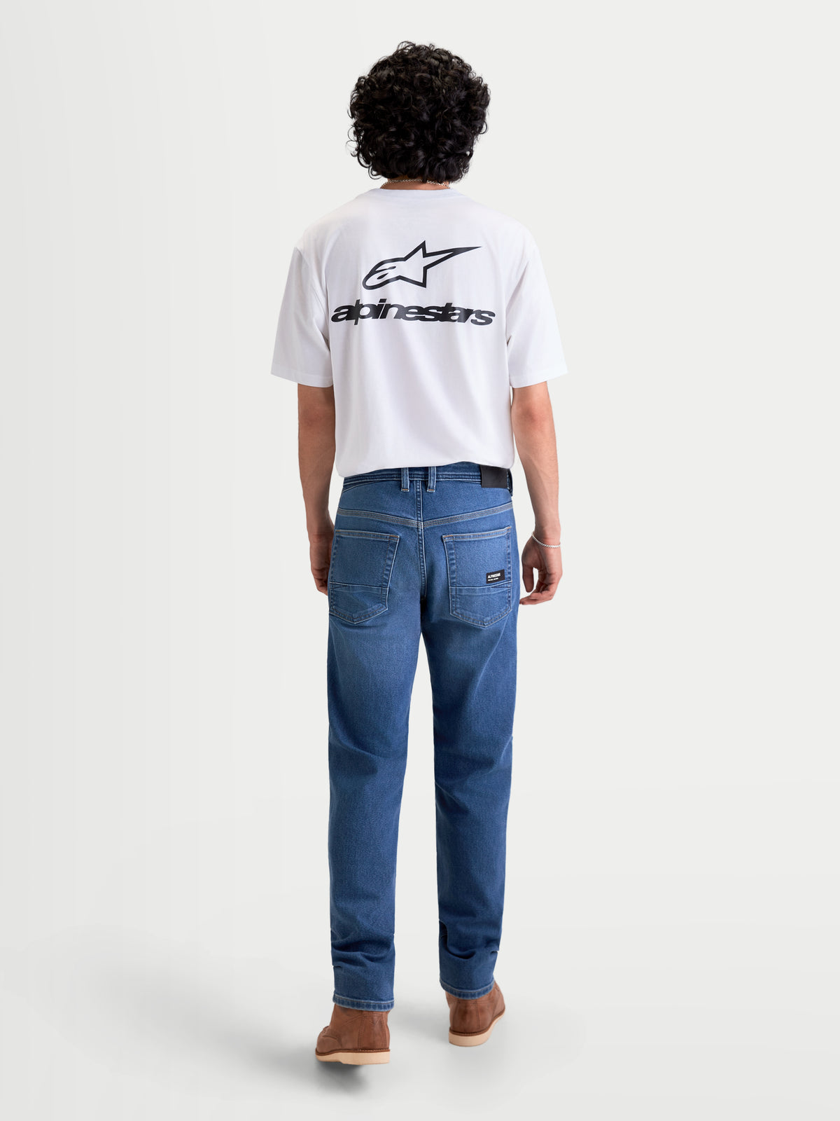 Alpinestars Flex Ast 7 Denim Pantaloni, jeans da moto urbani da uomo in azzurro, vista posteriore su un modello con maglietta bianca, con denim tecnico monostrato certificato AA e design a cinque tasche con dettaglio della toppa posteriore