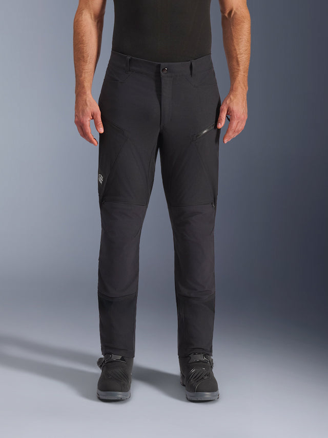 Alpinestars Flex-AST Explorer Pants, Black Motorcycle Pants, technical ripstop textile construction, worn with black adventure boots, featuring zippered cargo pockets and a multi-panel ergonomic design for adventure riding