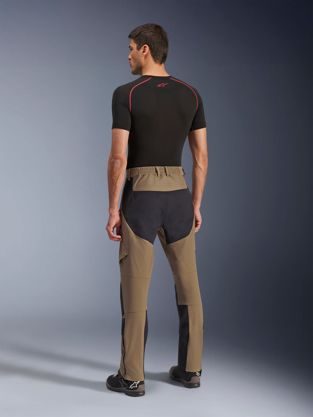 Pantaloni Alpinestars Flex-AST Explorer, pantaloni da moto adventure, Walnut Black, vista posteriore su modello con pannelli neri in ripstop su seduta e gambe, costruzione in tessuto elasticizzato e lunghe cerniere a fondo gamba per l'adventure touring