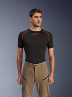 Pantaloni Alpinestars Flex-AST Explorer, pantaloni da moto adventure, Walnut Black, indossati da un modello con una maglia base layer nera, con tasche cargo diagonali con cerniera e costruzione in tessuto elasticizzato resistente.