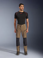 Pantaloni Alpinestars Flex-AST Explorer, pantaloni da moto touring, marrone walnut e nero, con pannelli rinforzati sulle ginocchia e tasche con zip sulle cosce, indossati con base layer nero a maniche corte, vista a figura intera