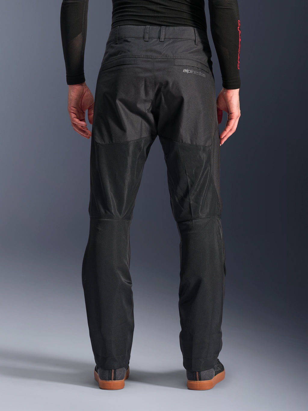 Alpinestars C-1 Air Pants, vista posteriore, nero, pantaloni da moto urbani in tessuto con ampi pannelli in mesh tecnica sul retro delle gambe per la ventilazione, design essenziale con logo discreto, indossati con base layer nero e scarpe da guida casual