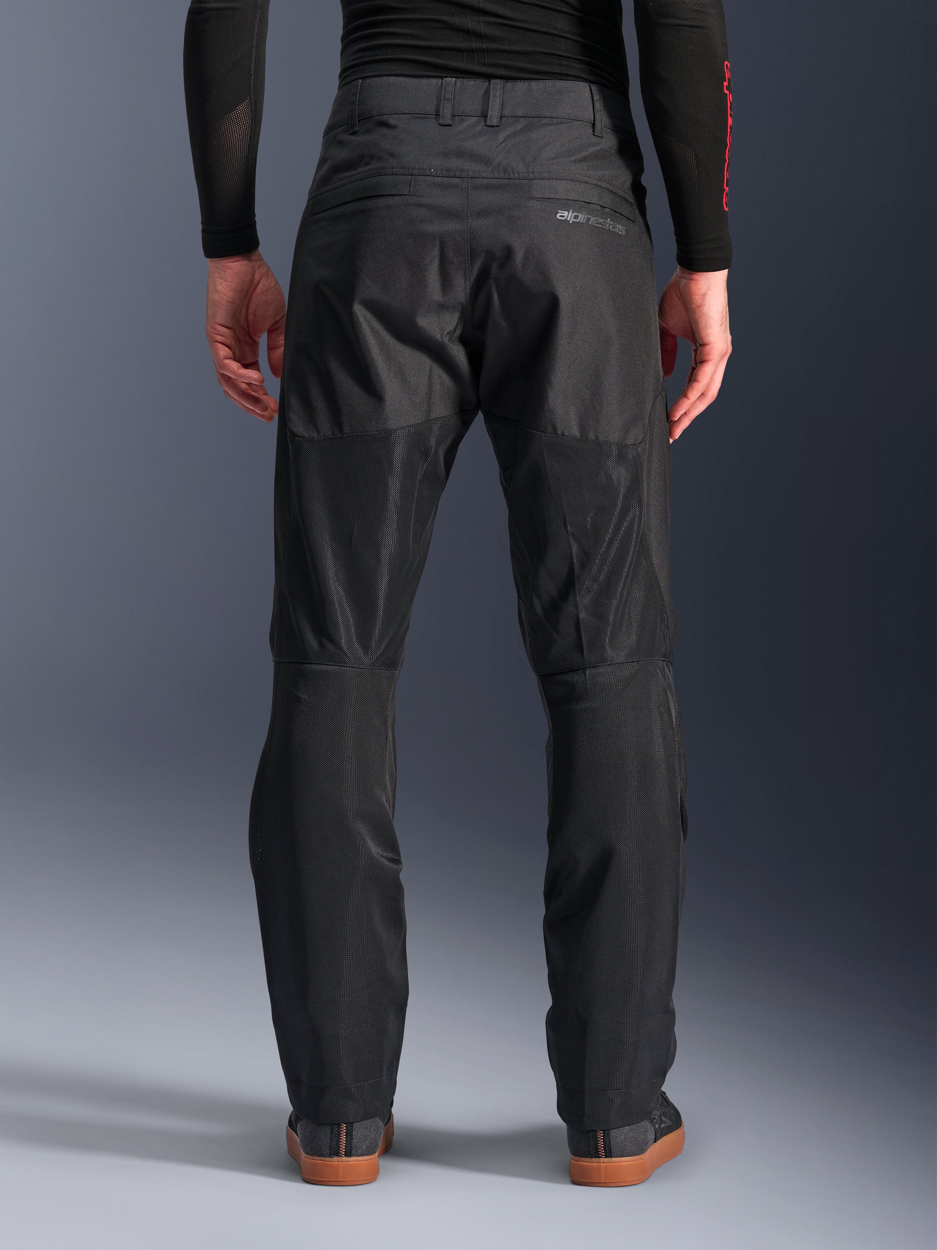 Alpinestars C-1 Air Pants, vista posteriore, nero, pantaloni da moto urbani in tessuto con ampi pannelli in mesh tecnica sul retro delle gambe per la ventilazione, design essenziale con logo discreto, indossati con base layer nero e scarpe da guida casual