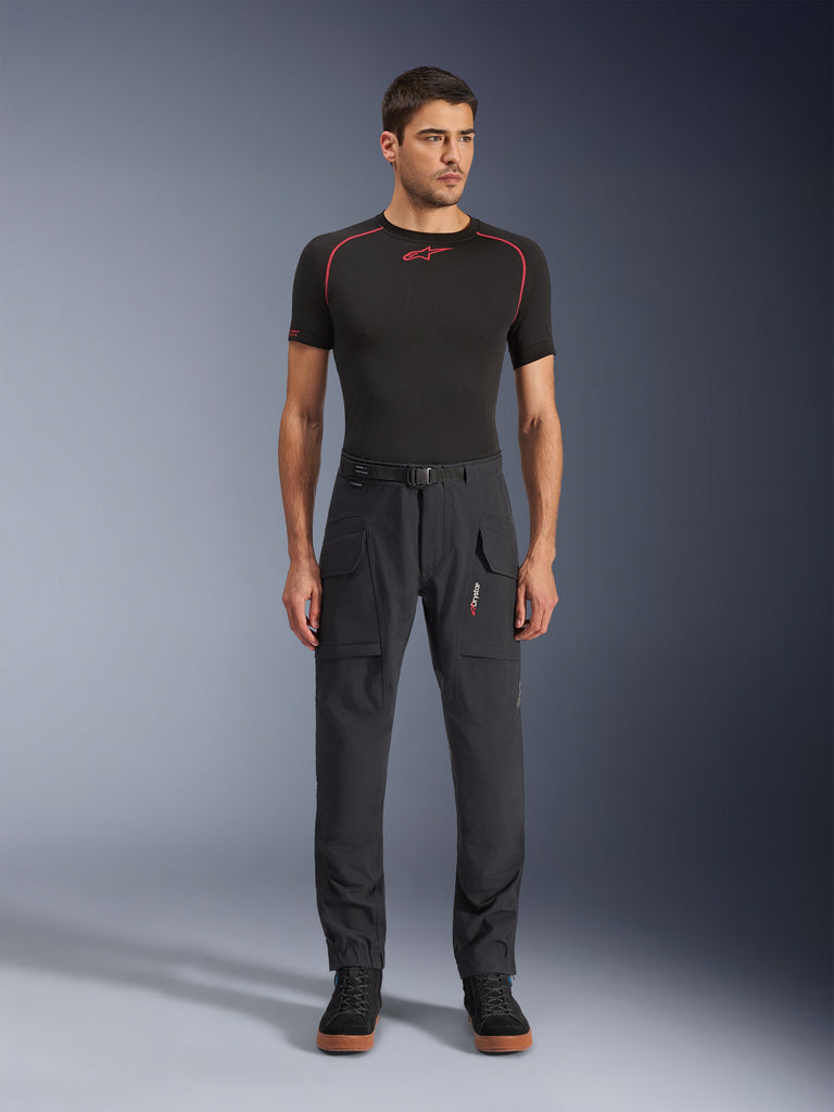 Alpinestars Juggernaut V2 Riding Pants, pantaloni da moto tecnici, neri con tasche cargo, indossati da uomo con camicia nera e dettagli rossi, design sportivo e funzionale