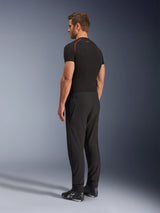 Pantaloni Alpinestars Aeroshell Airflow, pantaloni da moto neri, leggero tessuto softshell, indossati con maglia tecnica nera a maniche corte e stivali da moto neri, vista laterale posteriore che mostra la vestibilità slim e la costruzione ergonomica