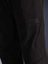 Alpinestars Aeroshell Airflow Pants, pantaloni da moto neri, vista ravvicinata della zona della coscia con logo ASTARS nero a rilievo, materiale softshell elasticizzato leggero con design ergonomico delle cuciture