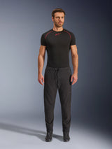 Modello che indossa i pantaloni Alpinestars Aeroshell Airflow neri, abbinati a un base layer nero a maniche corte e stivali da moto neri. Questi pantaloni da moto in softshell leggero presentano una vita con coulisse e polsini elastici, progettati per motociclisti sport e touring in condizioni di clima caldo.