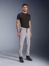 Pantaloni Alpinestars Aeroshell Airflow, pantaloni da moto, grigio medio, indossati da un modello con t-shirt tecnica nera e scarpe da moto nere, caratterizzati da zone di ventilazione traforate al laser, vita elastica con cordino e vestibilità sportiva aerodinamica.