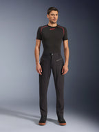 Pantaloni Alpinestars Flex-AST Canvas, pantaloni da moto urbani, nero, indossati da un modello con un base layer nero a maniche corte con cuciture rosse e sneakers casual nere, che mette in risalto le tasche anteriori con cerniera e il design ergonomico in tela.