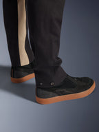 Pantaloni Alpinestars Flex-AST Canvas in Black Aluminum, primo piano della parte inferiore della gamba con regolazioni a pressione e striscia verticale color alluminio, abbinati a sneakers da moto nere con suola gum, abbigliamento moto urbano.