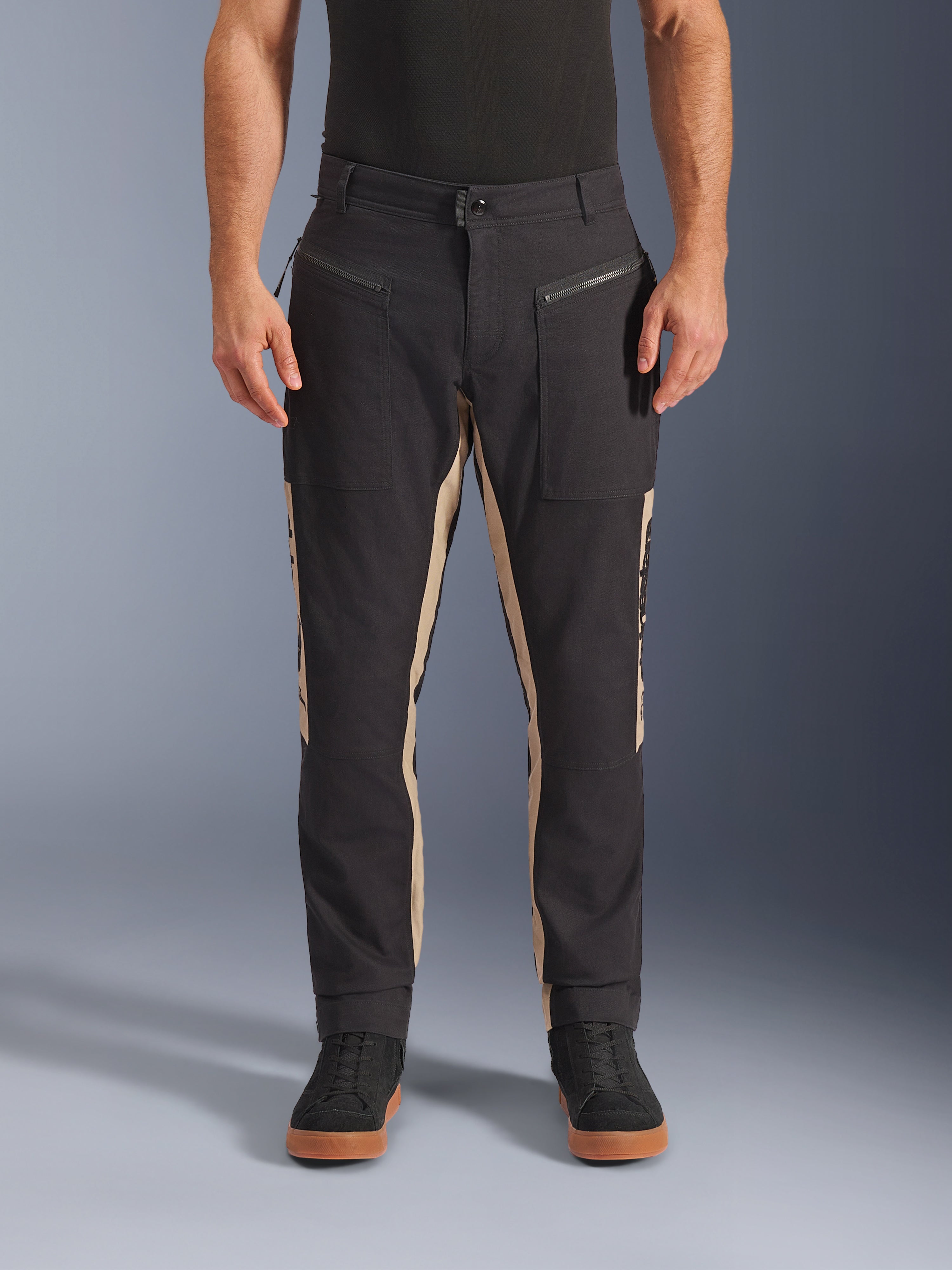 Alpinestars Flex-AST Canvas Pants, pantaloni da moto urbani, nero e alluminio, design workwear ispirato all'heritage, tasche anteriori con zip, taglio moto ergonomico, indossati con sneaker nere e t-shirt nera, stile street funzionale