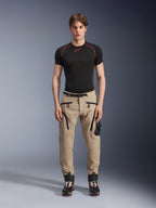Modello che indossa pantaloni Alpinestars Acteon in colorazione Sand, abbinati a un base layer nero a maniche corte e stivali tecnici neri, con tasche cargo, zip nere e vestibilità affusolata, abbigliamento da moto urban contemporaneo