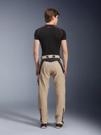 Alpinestars Acteon Pants in Sand, moderni pantaloni da moto urban visti dal retro, con pannelli neri e logo Alpinestars bianco, vestibilità affusolata con zip sul fondo, indossati con base layer nero a maniche corte e sneakers.