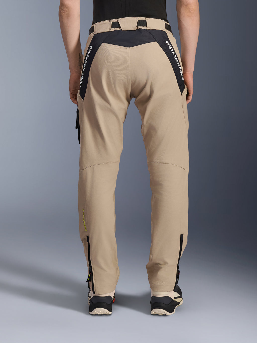 Alpinestars Pantaloni Acteon, pantaloni da moto urbani, sabbia, vista posteriore con pannelli ripstop neri e logo bianco sullo sprone, vestibilità affusolata con cerniere sulla parte inferiore della gamba, abbigliamento da moto contemporaneo
