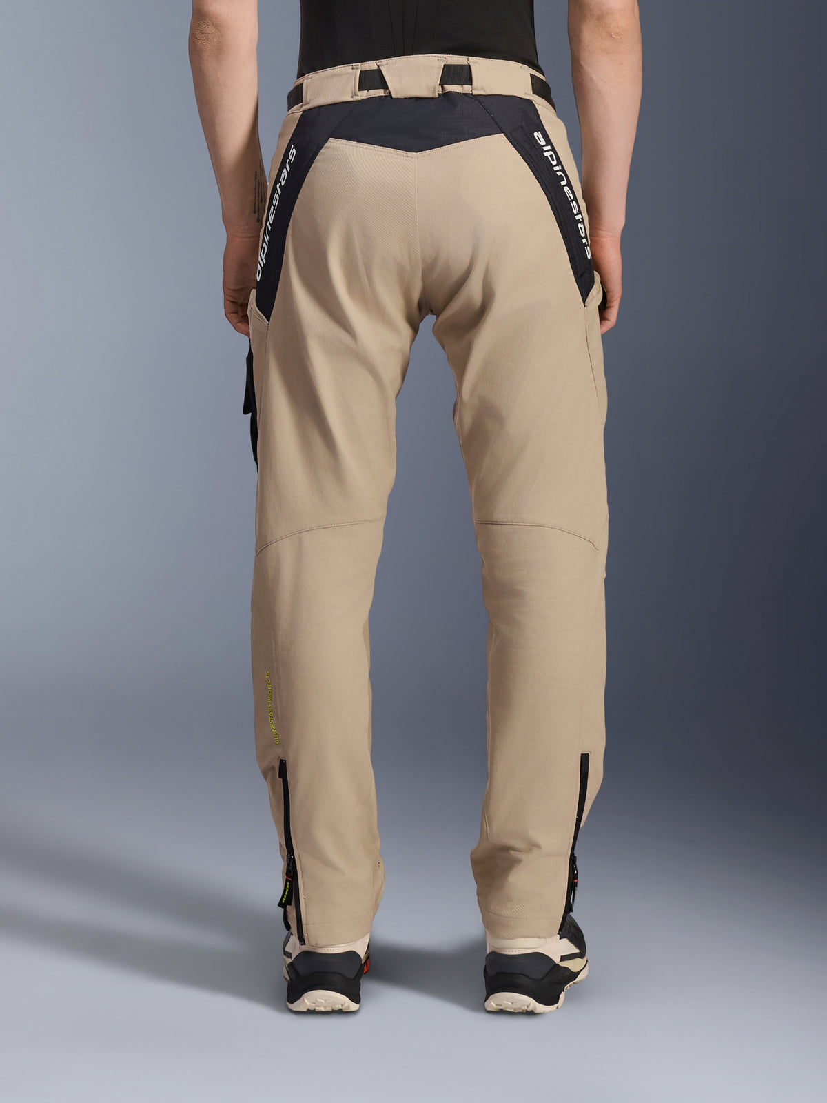 Alpinestars Pantaloni Acteon, pantaloni da moto urbani, sabbia, vista posteriore con pannelli ripstop neri e logo bianco sullo sprone, vestibilità affusolata con cerniere sulla parte inferiore della gamba, abbigliamento da moto contemporaneo