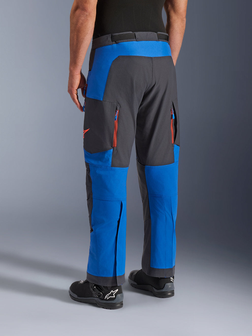 Pantaloni Alpinestars Maxdura Dual, Blu Royal e Deep Gray, vista posteriore con tasche con zip e zone di ventilazione, design sopra-stivale indossato con stivali Alpinestars neri, abbigliamento resistente per guida adventure e dual-sport