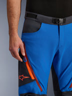 Alpinestars Maxdura Dual Pants in Royal Blue e Deep Gray, vista ravvicinata del girovita con fibbia magnetica, tasca cargo con zip e dettagli arancioni, logo Alpinestars rosso, abbigliamento tecnico da moto per avventura