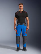 Alpinestars Maxdura Dual Pants, pantaloni da moto adventure, blu reale e grigio scuro, accenti con cerniere arancioni, indossati con base layer Alpinestars nero e stivali neri, con pannelli rinforzati sulle ginocchia e design tecnico da fuoristrada