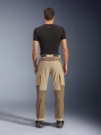 Alpinestars Maxdura Dual Pants in Walnut Aluminum, vista posteriore che mostra il design bicolore marrone e beige, pantaloni da moto adventure con tasche cargo con zip e seduta rinforzata, indossati con maglia a compressione nera e stivali da moto
