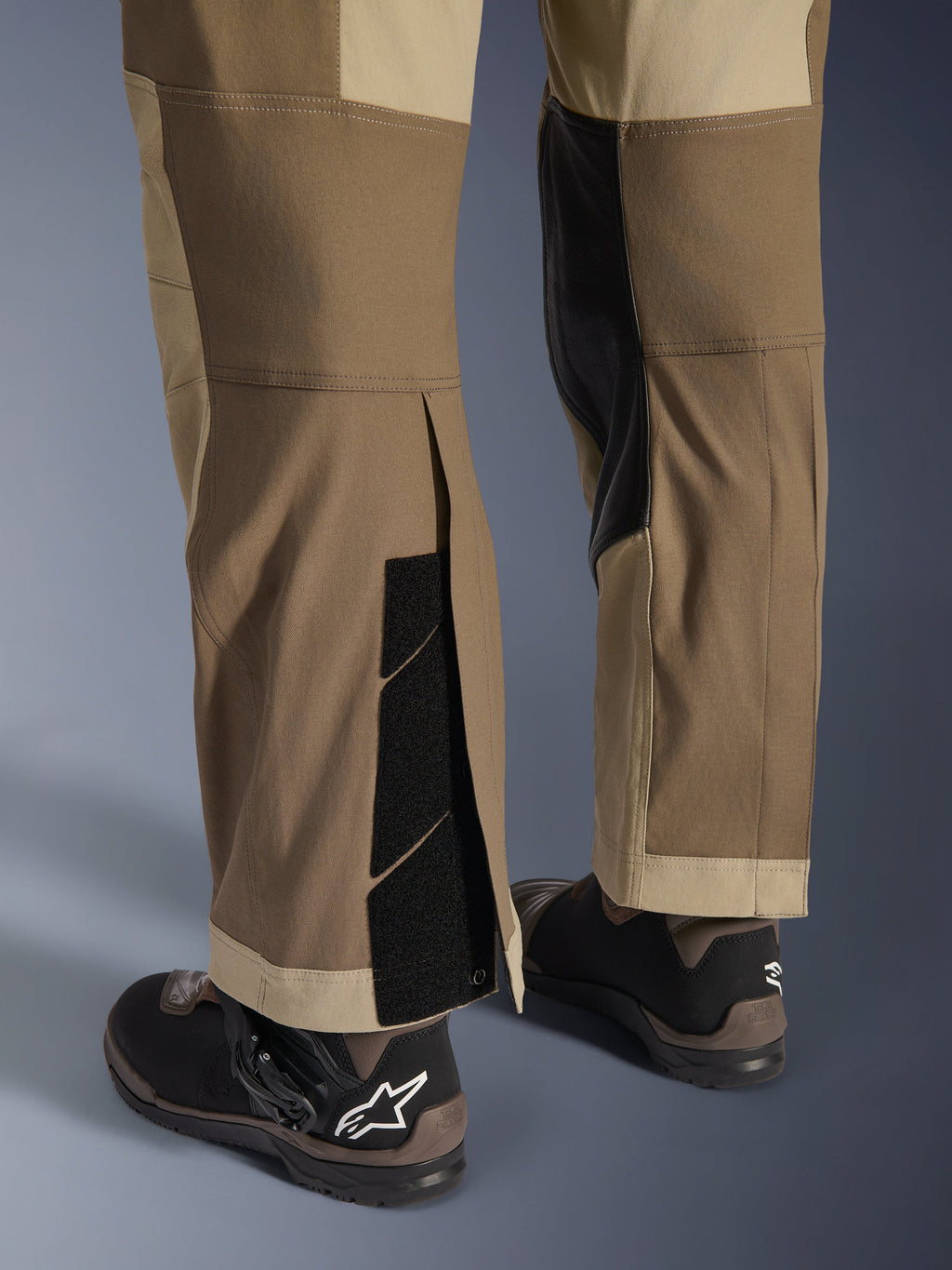 Alpinestars Maxdura Dual Pants in Walnut Aluminum, vista dettagliata della parte inferiore della gamba e dell'orlo con design sopra lo stivale, chiusure a strappo regolabili e pannelli interni rinforzati, abbinati a stivali da moto neri