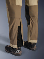 Alpinestars Maxdura Dual Pants in Walnut Aluminum, vista dettagliata della parte inferiore della gamba e dell'orlo con design sopra lo stivale, chiusure a strappo regolabili e pannelli interni rinforzati, abbinati a stivali da moto neri
