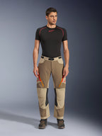 Alpinestars Maxdura Dual Pants, pantaloni da moto Adventure e Dual-Sport, Walnut Aluminum, indossati con una maglia a compressione nera a maniche corte e stivali adventure, caratterizzati da prese d'aria arancioni con cerniera e loghi rossi sulle cosce, cintura nera in vita con fibbia, design sopra lo stivale per la guida in moto.
