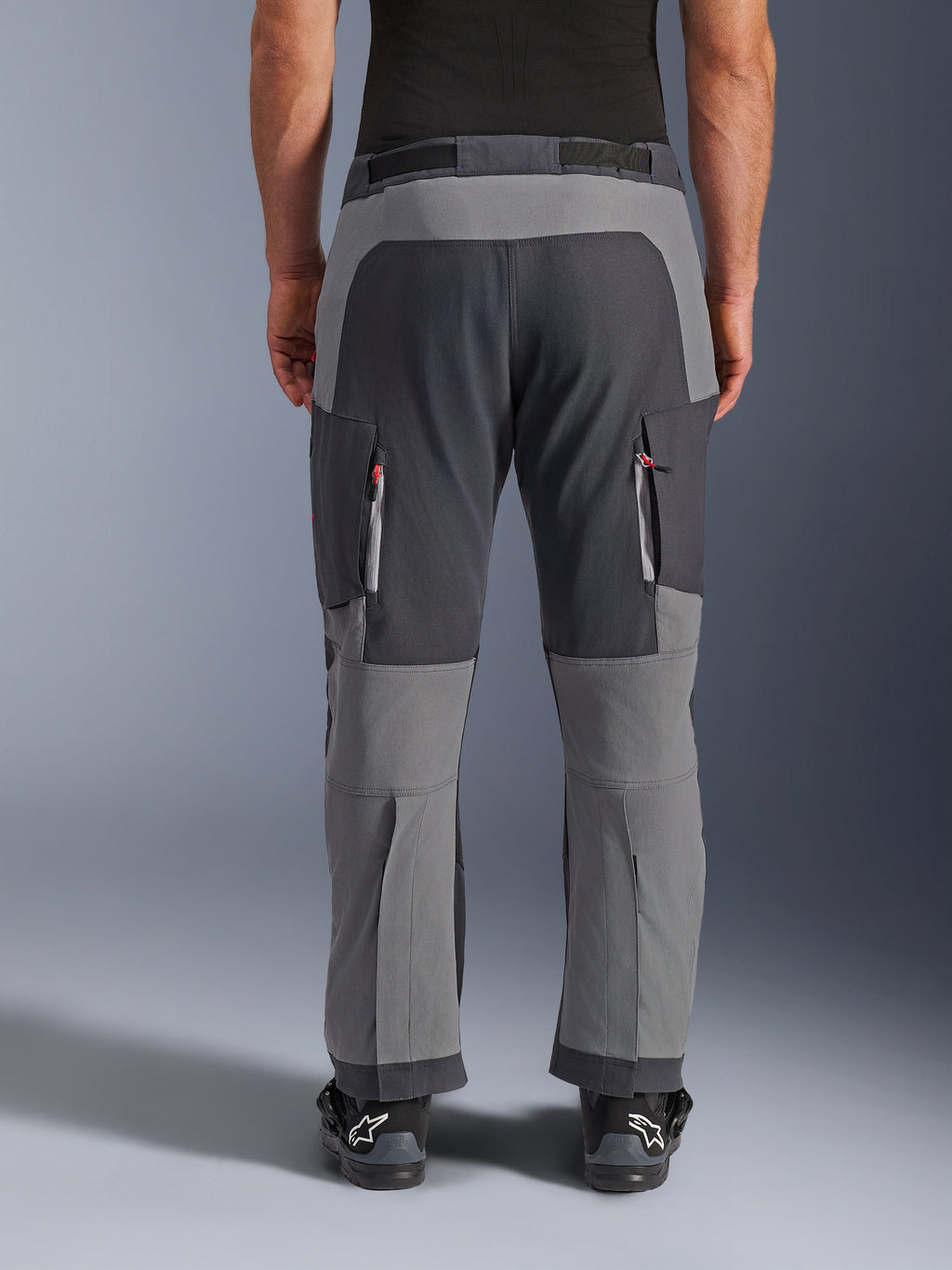 Alpinestars pantaloni Maxdura Dual, pantaloni da moto adventure, grigio scuro e grigio intenso, vista posteriore con pannelli rinforzati su seduta e ginocchia, prese d'aria con cerniera sulle cosce, indossati con stivali Alpinestars neri, robusta costruzione in poliammide elasticizzata per guida dual-sport.