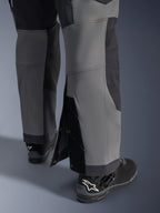 Alpinestars pantaloni Maxdura Dual, pantaloni da moto adventure, grigio scuro e grigio intenso, vista ravvicinata dell'orlo regolabile sopra lo stivale con bottoni a pressione e pannelli rinforzati, indossati con stivali Alpinestars neri, design tecnico robusto per guida dual-sport