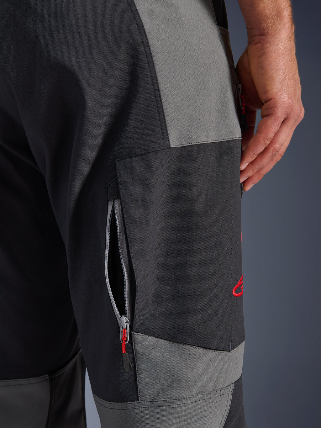Alpinestars Maxdura Dual Pants, pantaloni da moto adventure in Dark Gray e Deep Gray, primo piano della coscia con presa d'aria con cerniera e logo ricamato rosso, struttura in poliammide elasticizzata resistente