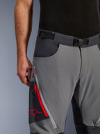 Alpinestars Maxdura Dual Pants, pantaloni da moto adventure, grigio scuro e grigio intenso, primo piano con cintura regolabile con fibbia magnetica, tasca cargo con zip con dettagli rossi e logo Alpinestars.