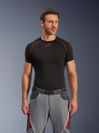 Pantaloni Alpinestars Maxdura Dual, grigio scuro e grigio intenso con accenti rossi, indossati con una maglia base layer nera con cuciture rosse, vestibilità atletica con cintura integrata a fibbia magnetica, abbigliamento resistente per moto adventure
