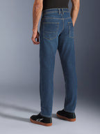 Alpinestars Flex-AST 5 Denim Pants, blu Indigo Washed, vista posteriore di una persona che indossa jeans da moto casual con vestibilità affusolata, abbinati a sneakers Alpinestars nere, con tasche posteriori e cuciture rinforzate per la guida urbana