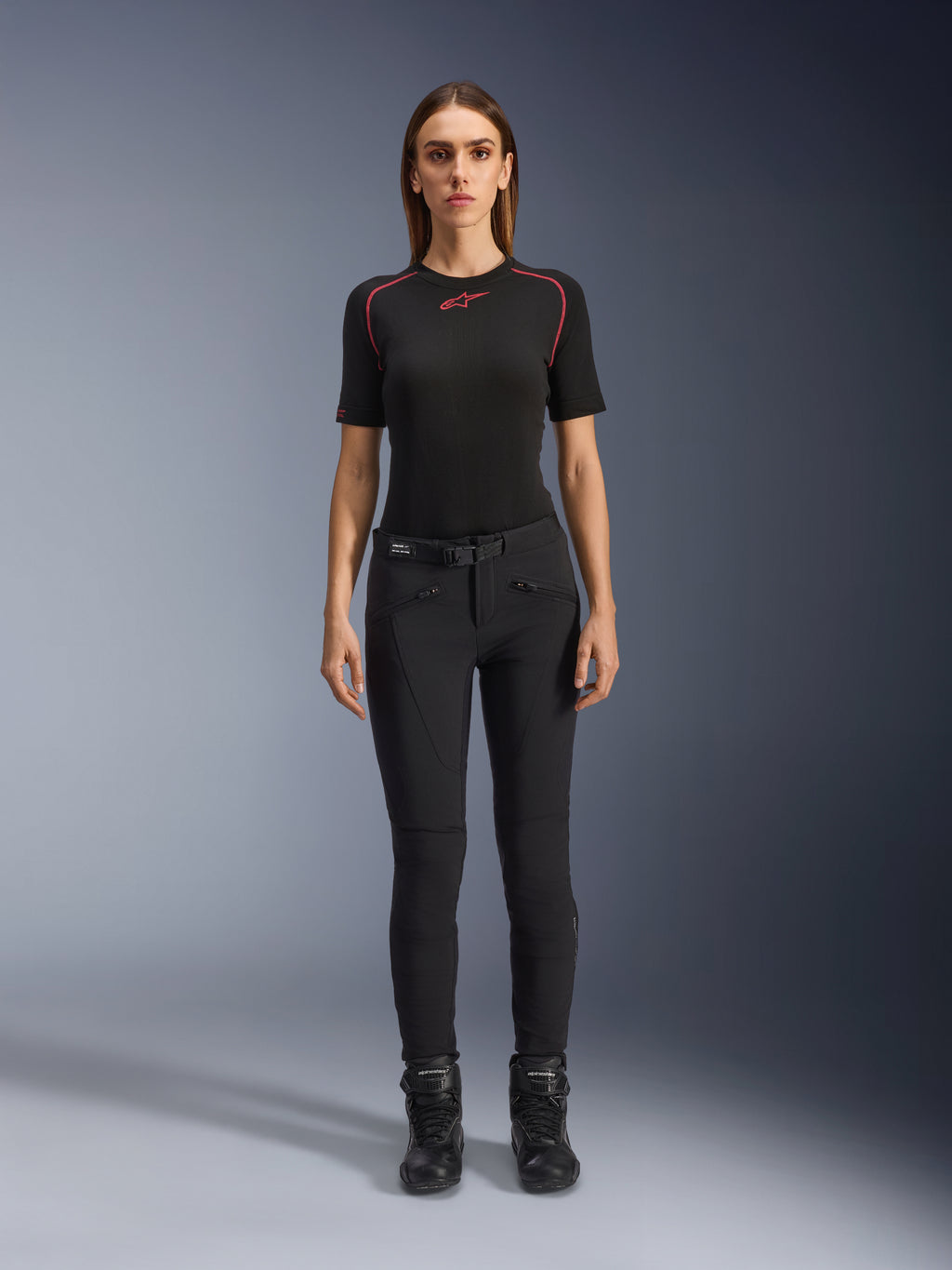 Pantaloni Alpinestars Alamosa Donna, pantaloni da moto neri slim-fit, indossati da una modella in posizione frontale, con tasche anteriori dotate di zip e cintura in vita integrata, stile minimalista ispirato allo streetwear per la guida urbana