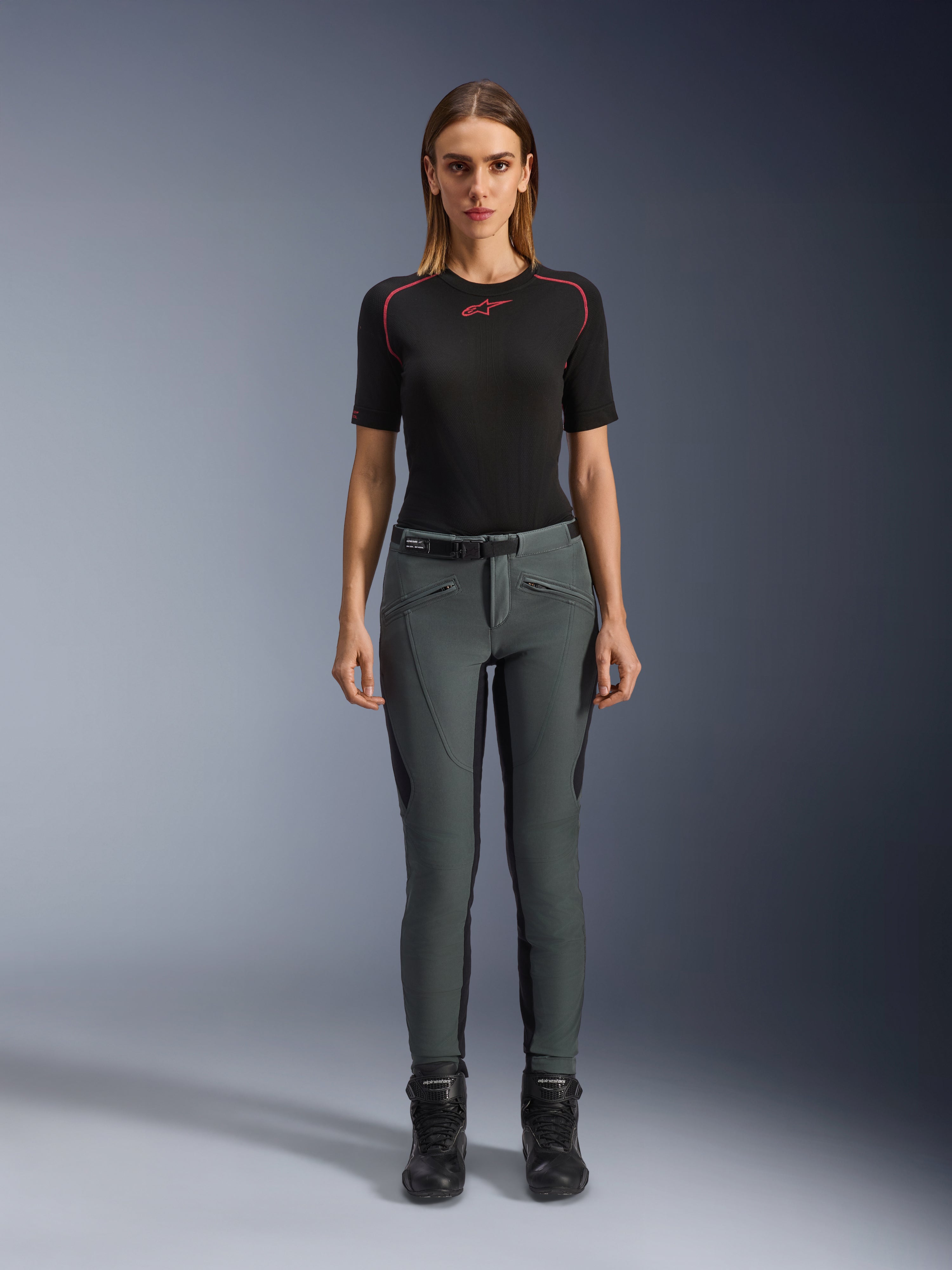 Alpinestars Pantaloni Alamosa, pantaloni da moto slim fit da donna, grigio urbano, in softshell elasticizzato con protezioni CE, indossati con maglia e stivali neri, stile urban streetwear