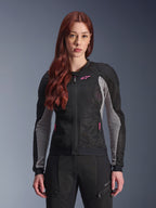Giacca Alpinestars Stella Troop-Air da donna, giacca da moto traforata, nero, grigio cenere e rosa fluo, indossata da una modella con pantaloni coordinati, costruzione in mesh tecnico 2D ventilato e dettagli del logo rosa, ideale per la guida urbana estiva