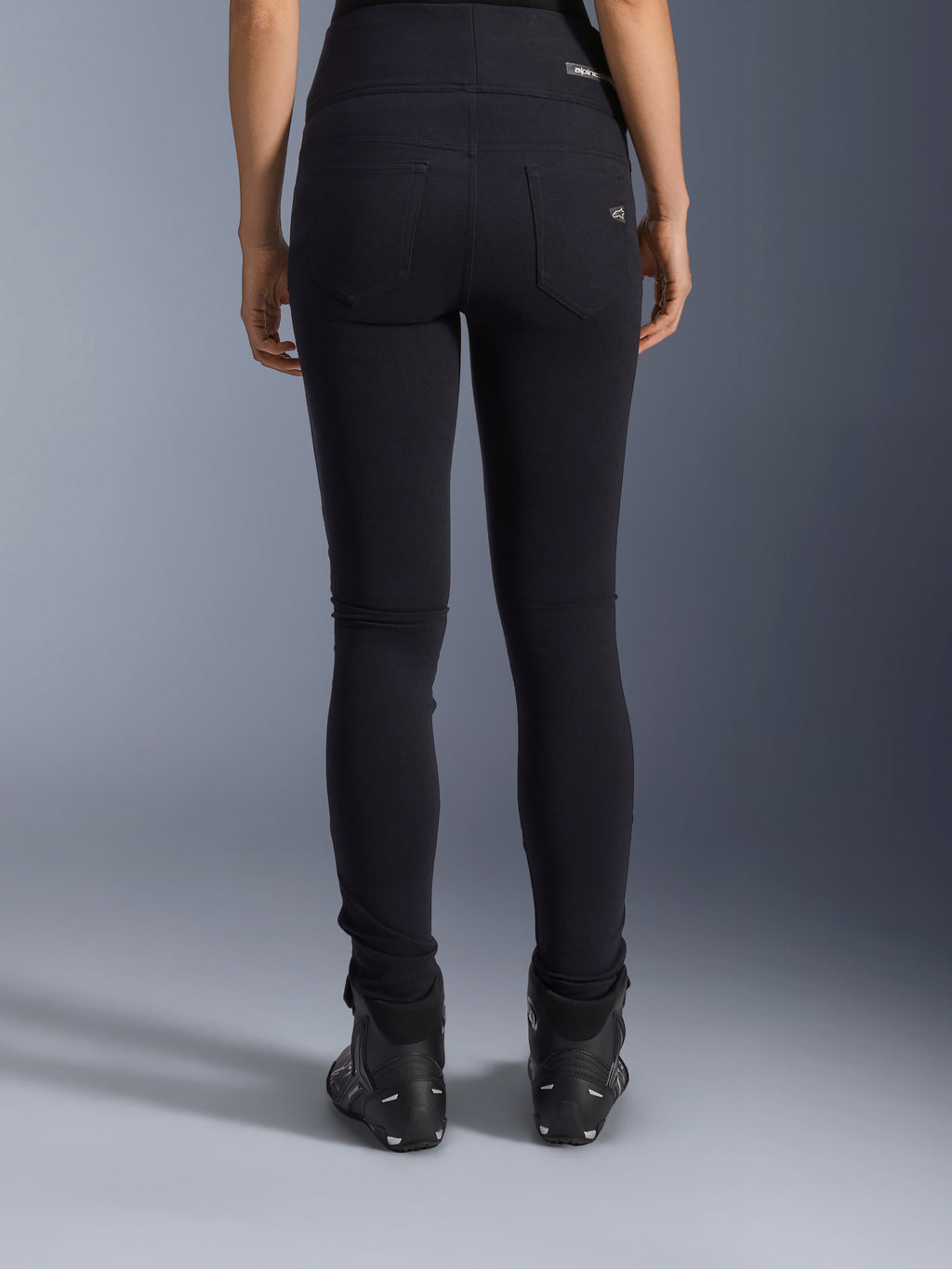 Alpinestars Leggings Stella Flex-Ast, leggings da moto da donna, nero, vista posteriore con tasche posteriori e vestibilità slim, indossati con stivali da moto neri, stile urban riding