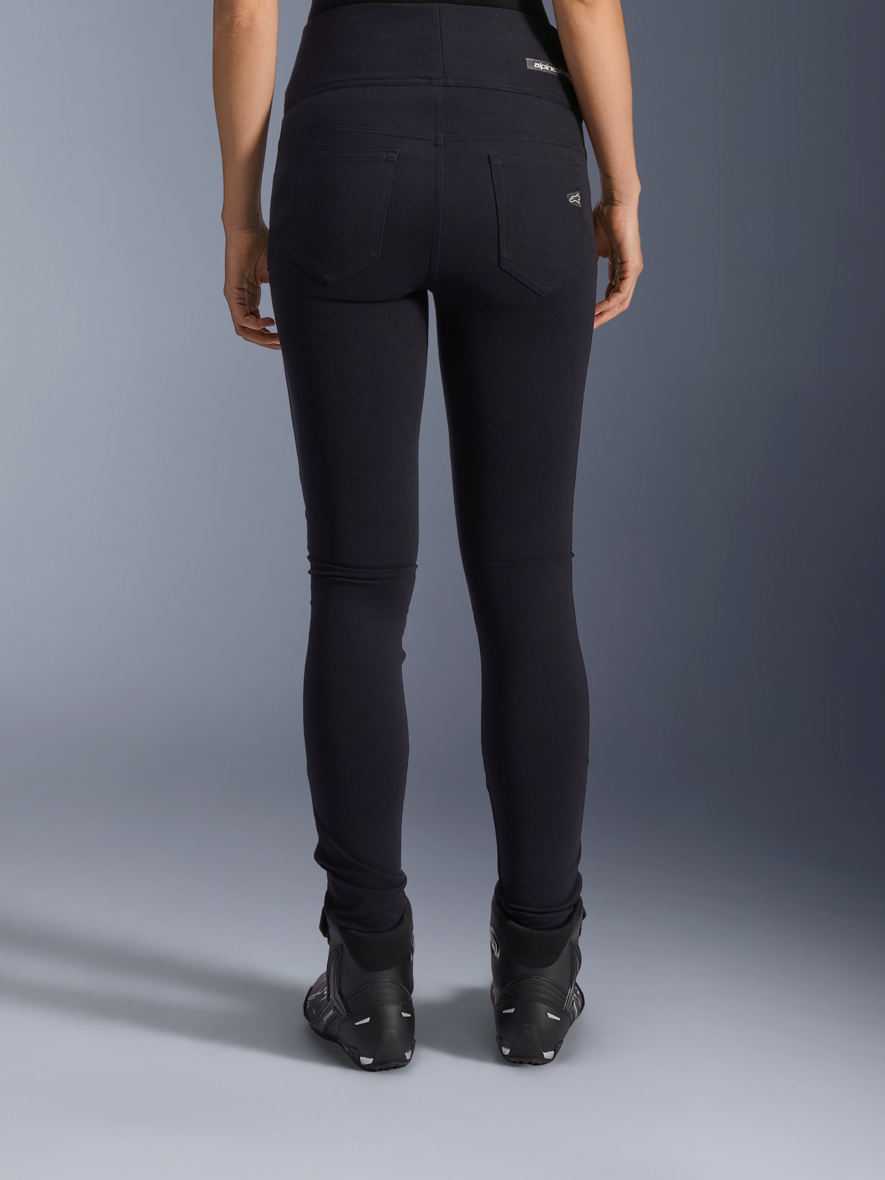 Alpinestars Leggings Stella Flex-Ast, leggings da moto da donna, nero, vista posteriore con tasche posteriori e vestibilità slim, indossati con stivali da moto neri, stile urban riding