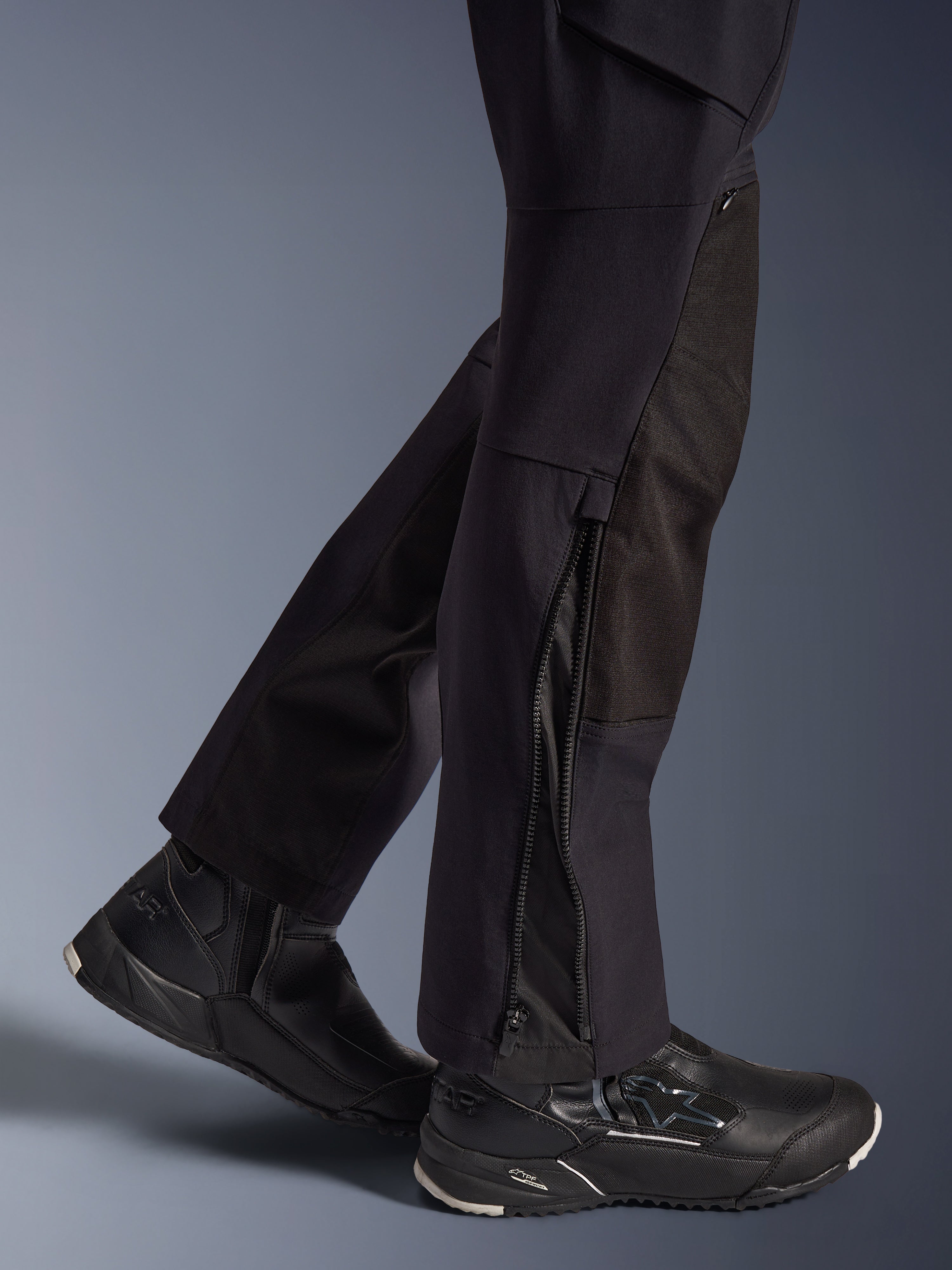 Pantaloni Alpinestars Stella Flex-AST Explorer, pantaloni da moto da donna, nero, vista ravvicinata della parte inferiore delle gambe con orli dotati di cerniera e rinforzi resistenti in ripstop, indossati con scarpe da moto Alpinestars nere