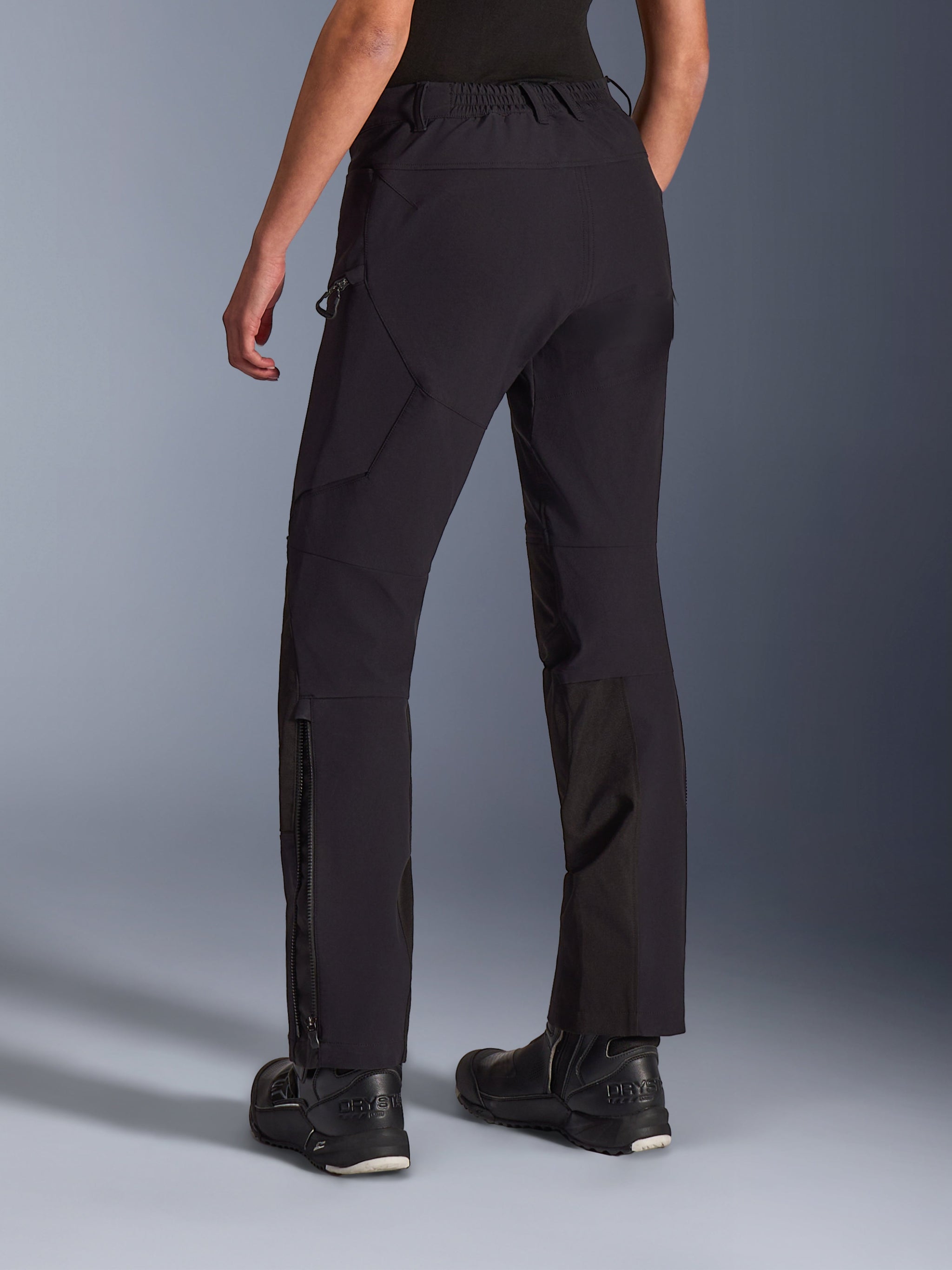 Alpinestars Stella Flex-AST Explorer Pants, pantaloni da moto da donna, nero, vista posteriore su modella, con orli delle gambe dotati di cerniera e tasche cargo, tessuto elasticizzato leggero con rinforzi in ripstop, abbinati a stivali da moto neri