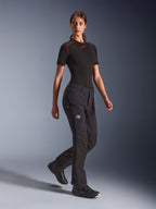 Alpinestars Woman Stella Flex-AST Explorer Pants, pantaloni da moto adventure neri, con costruzione in tessuto elasticizzato e rinforzi in ripstop, tasche cargo con zip e cerniere sul fondo gamba, indossati con base layer nero a maniche corte e scarpe da moto.