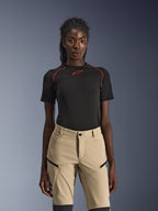 Alpinestars Stella Flex-AST Explorer Pants, pantaloni da moto da donna color sabbia, indossati con un top tecnico nero a maniche corte con cuciture rosse, abbigliamento da adventure touring con tasche cargo con zip e resistente tessuto ripstop.
