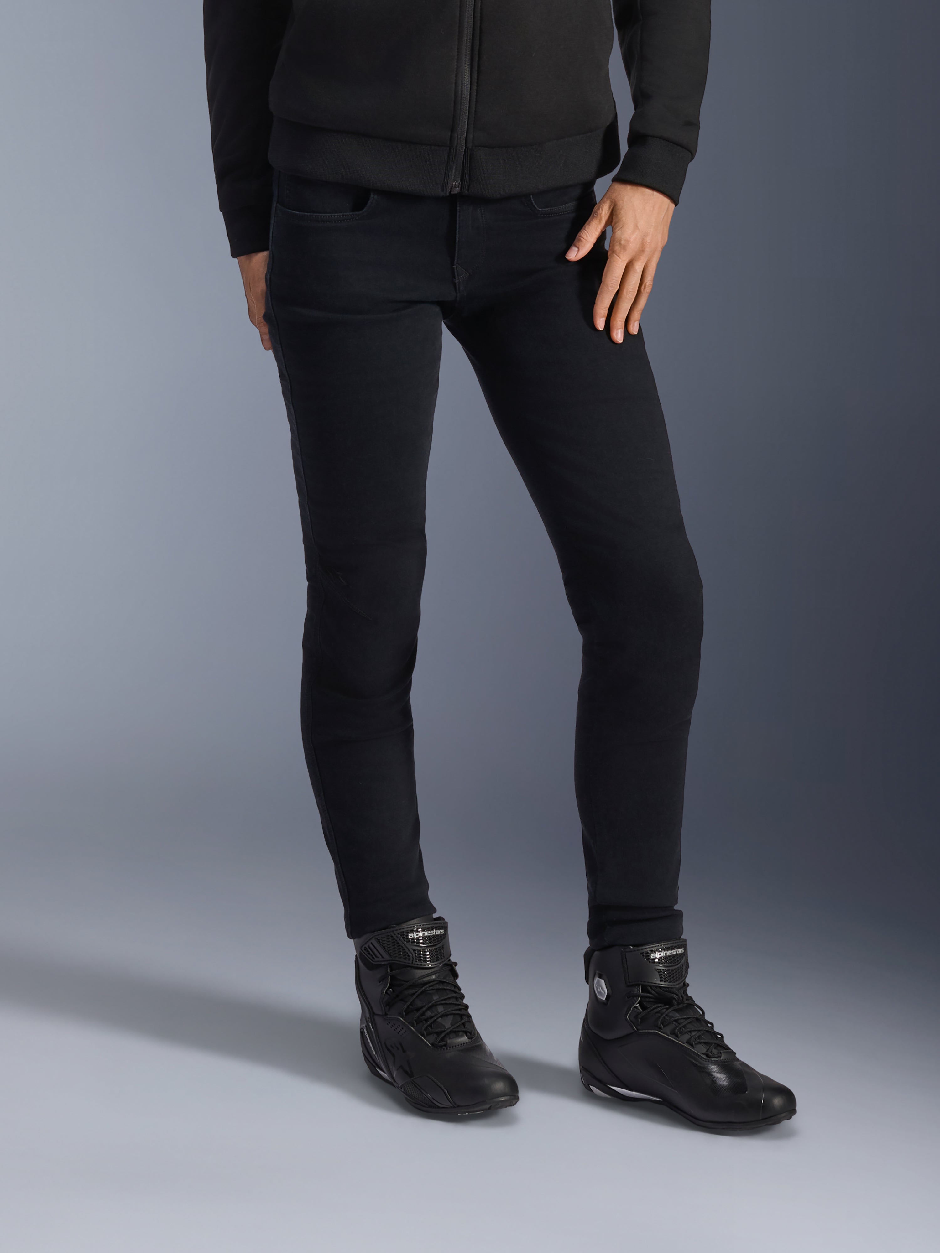 Alpinestars Daisy V3 Women's Riding Denim, Rinse Black, jeans da moto vestibilità slim, abbinati a stivali da moto alti neri e felpa con zip, stile urbano monocromatico elegante