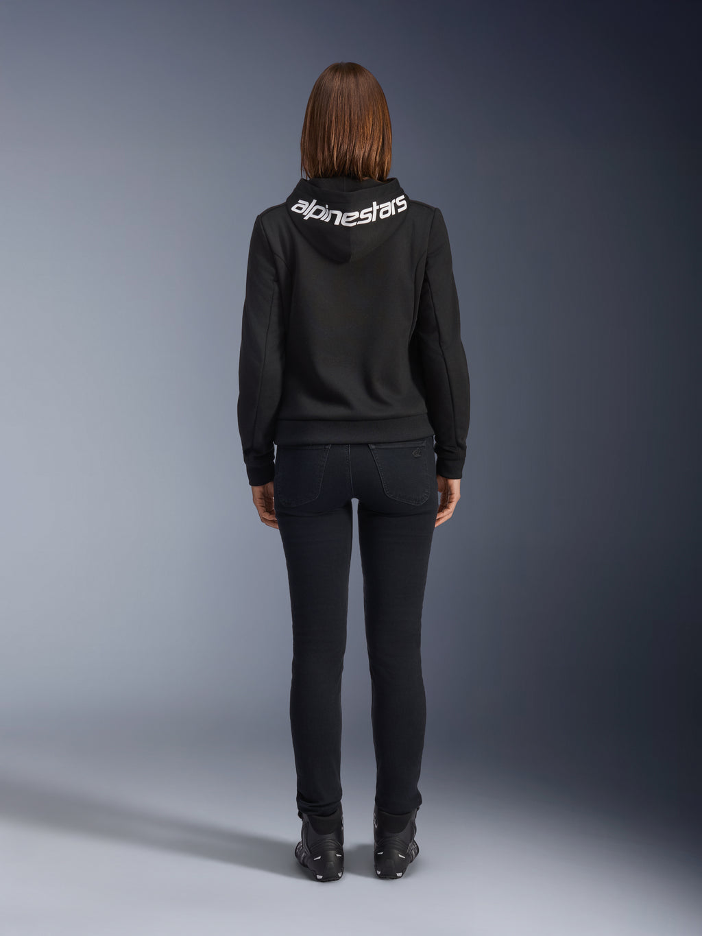 Daisy V3 Jeans da moto da donna, Black Rinse, pantaloni slim fit, vista posteriore con vita alta e silhouette femminile, abbinati a una felpa nera Alpinestars e stivali da moto neri, abbigliamento da guida urban casual