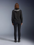 Daisy V3 Jeans da moto da donna, Black Rinse, pantaloni slim fit, vista posteriore con vita alta e silhouette femminile, abbinati a una felpa nera Alpinestars e stivali da moto neri, abbigliamento da guida urban casual