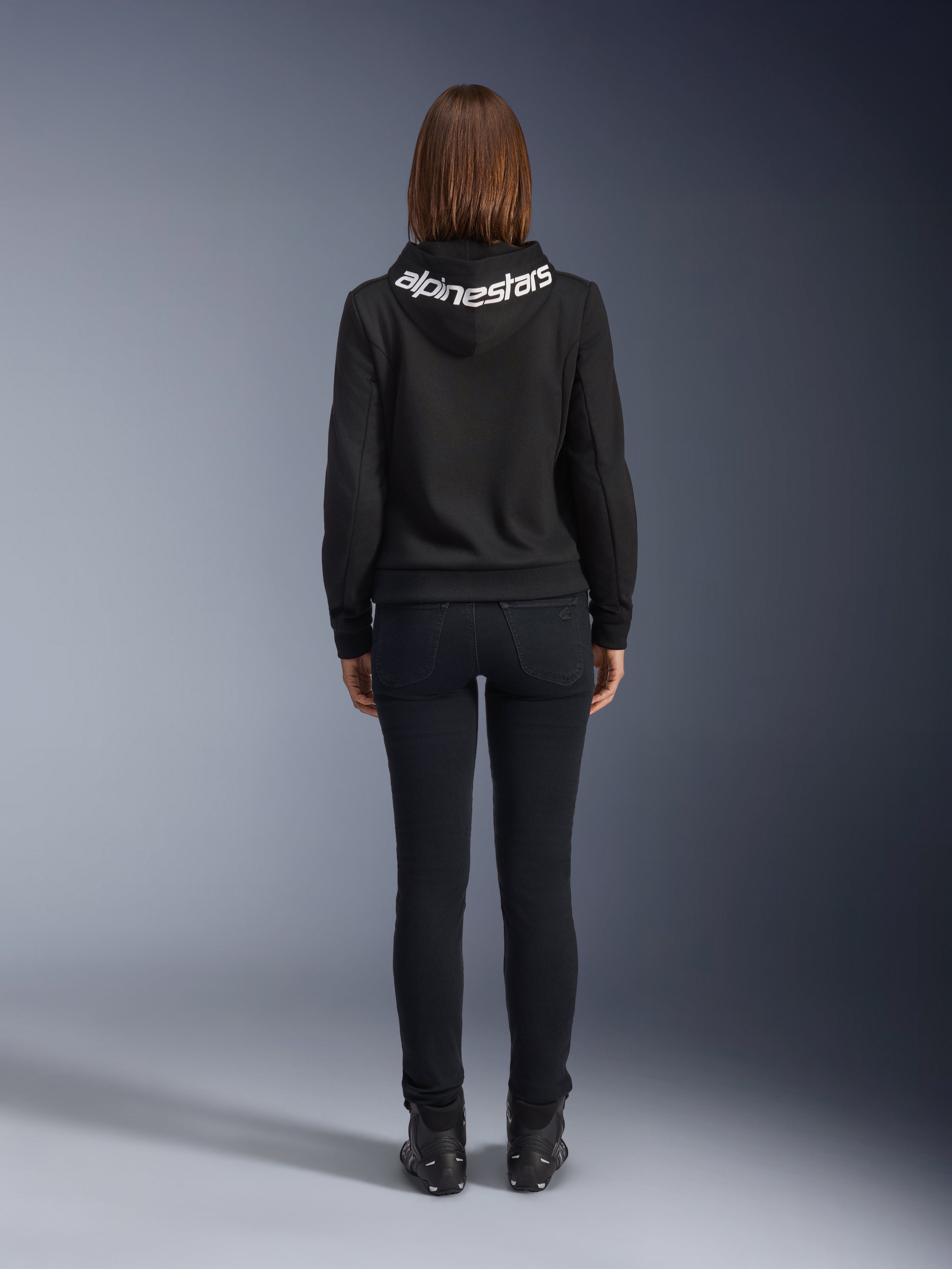 Daisy V3 Jeans da moto da donna, Black Rinse, pantaloni slim fit, vista posteriore con vita alta e silhouette femminile, abbinati a una felpa nera Alpinestars e stivali da moto neri, abbigliamento da guida urban casual